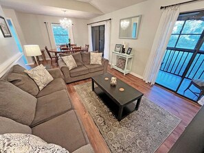 A living room with a sofa set, a coffee table, and a dining area with a chandelier. - CQS 26 Catalonia Ct Conquistador (St. Augustine)