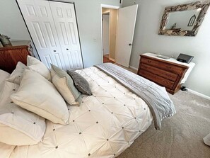 A bedroom with a bed, a dresser, a mirror, and a door. - CQS 26 Catalonia Ct Conquistador (St. Augustine)