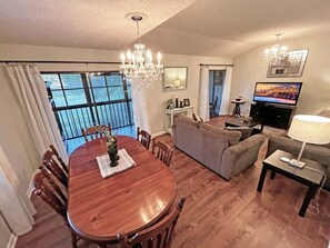 A living room with a dining table, sofas, a television, and a chandelier. - CQS 26 Catalonia Ct Conquistador (St. Augustine)