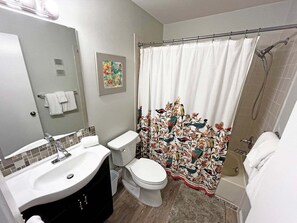 Un baño con cortina de ducha, inodoro, lavabo y espejo.
