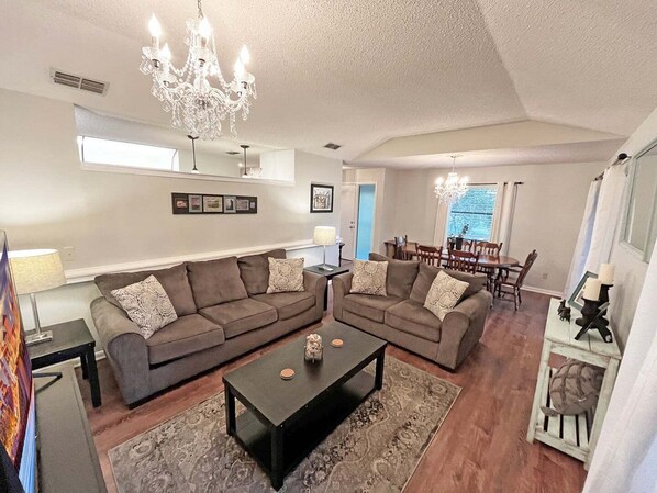 A spacious living room with two sofas, a coffee table, and a chandelier.