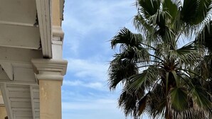 A building with a balcony overlooking a street with palm trees and parked cars. - Condo super close to the beach with a view of SpaceX Launch in the sky! (south padre island)
