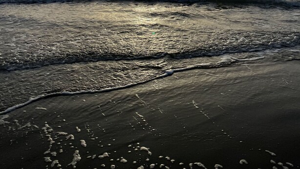 A beach with waves and the sun setting in the distance. - Condo super close to the beach with a view of SpaceX Launch in the sky! (south padre island)