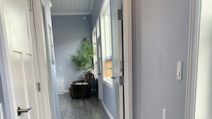Un couloir avec un plancher en bois, une plante en pot et une chaise.