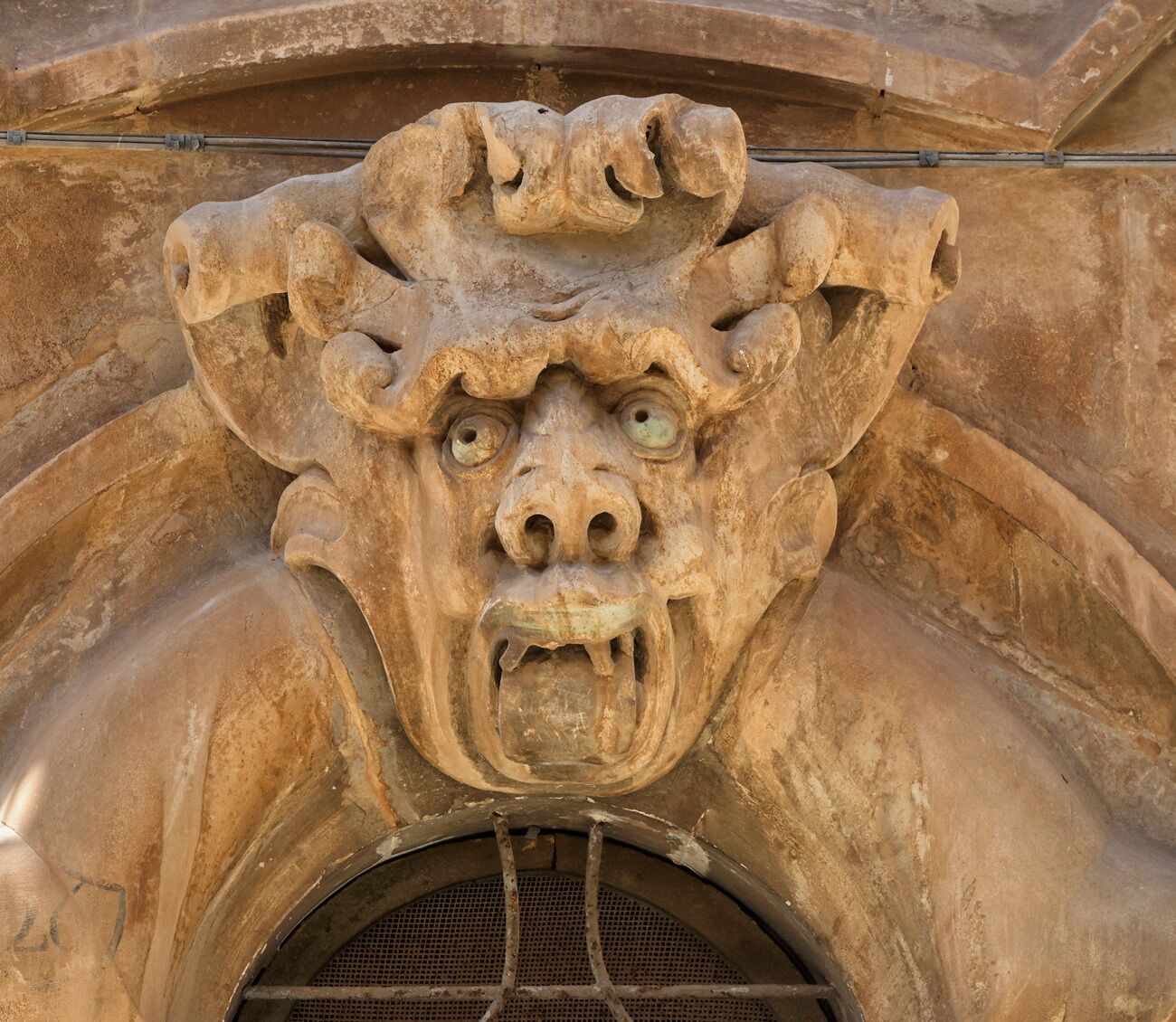 A stone gargoyle with a fierce expression, part of a building's architecture.