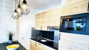 A modern kitchen with wooden cabinets, a black countertop, a stainless steel sink, and a built-in oven.