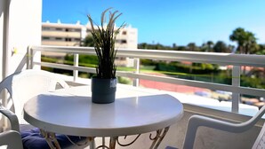 A balcony with a small table and a potted plant.