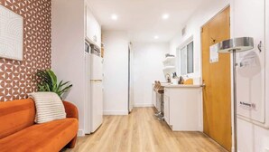 Een moderne keuken met witte kastjes, een houten vloer en een eethoek met een tafel en stoelen.