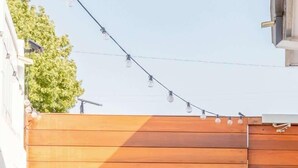 A small patio with two white chairs, a round table, and a potted plant. - Bright Modern Stay | Near LAX & Stadiums I Patio (Los Angeles)