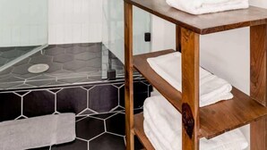 A modern bathroom with a glass shower, a wooden vanity with towels, and a potted orchid. - Bright Modern Stay | Near LAX & Stadiums I Patio (Los Angeles)