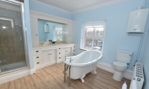 Ein Badezimmer mit einer freistehenden Badewanne, einer Toilette, einer Duschkabine und einem Fenster mit Blick hinaus.