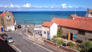 A coastal street with buildings, a clear view of the sea, and a parking area. - Gull View -  a second floor apartment that sleeps 4 guests  in 2 bedrooms (Sheringham)