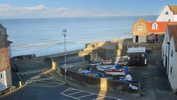 A coastal town with a view of the sea, boats docked at the harbor, and buildings with a mix of architectural styles. - Gull View -  a second floor apartment that sleeps 4 guests  in 2 bedrooms (Sheringham)