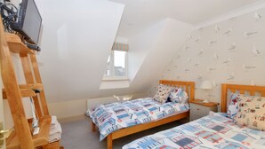 A bedroom with two beds, a wooden ladder, a desk, and a window. - Gull View -  a second floor apartment that sleeps 4 guests  in 2 bedrooms (Sheringham)