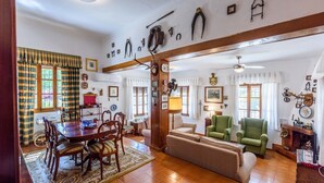 Un salon traditionnel comprenant un coin repas, un parquet et divers objets de décoration liés à la chasse, accrochés aux murs.