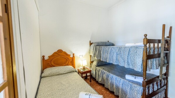 A small, compact room with a single bed, a nightstand, and a wooden chair. - Santa Ana de Marchena by Ruralidays (Seville)