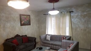Un salon avec deux canapés, une table basse et un luminaire suspendu au plafond.