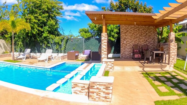 Un jardin avec une piscine, des meubles de patio et une pergola.