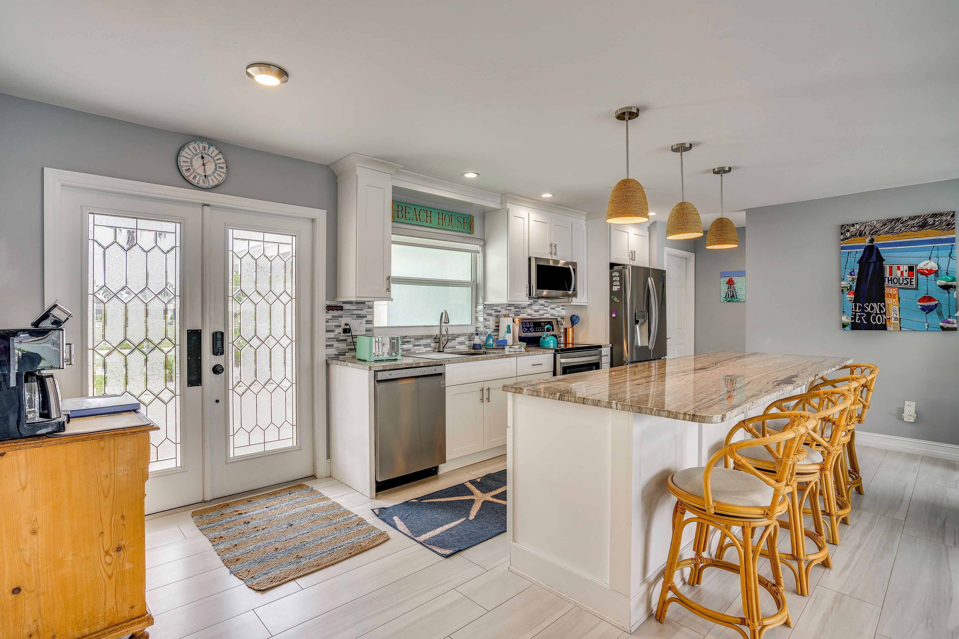 A modern kitchen with a central island, stainless steel appliances, and a dining area with wicker chairs.