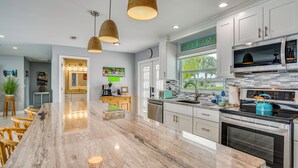 A modern kitchen with a large island, stainless steel appliances, and pendant lighting. - Canalfront Cape Coral Home with Dock & BBQ! (Cape Coral)