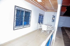 Ein Essbereich mit Tisch und Stühlen, einem dekorativen Metallfenstergitter und einer Decke mit sichtbaren Holzbalken.