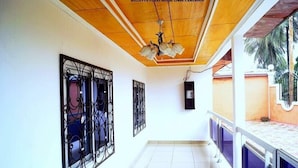 Un couloir doté d’un plafond en bois, de rampes décoratives en métal et d’un sol carrelé.