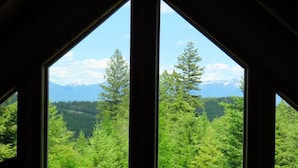 Ein Zimmer mit großen Fenstern und Blick auf eine bewaldete Berglandschaft.