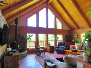 A cozy cabin with a large fireplace, wooden beams, and a spacious living area with a couch, chairs, and a coffee table. - Pinecrest Cabin- a relaxing mountain cabin close to town (Lakeside)