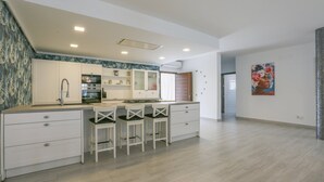A modern kitchen with white cabinets, a central island with bar stools, and a large window. - Villa M&J La Puebla de Cazalla by Ruralidays (Sevilla)