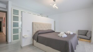 A modern bedroom with a large bed, a grey sofa, and a built-in wardrobe. - Villa M&J La Puebla de Cazalla by Ruralidays (Sevilla)
