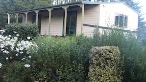 A single-story building with a porch, surrounded by dense vegetation and trees.