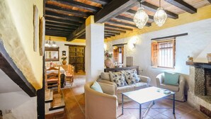 A cozy living room with a fireplace, a dining area with wooden furniture, and a staircase leading to another level. - Ventorro del Herrero  Gaucín by Ruralidays (Málaga)