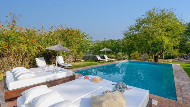 A poolside area with lounge chairs, a sunbed, and umbrellas. - Ventorro del Herrero  Gaucín by Ruralidays (Málaga)
