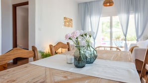A dining table with a white placemat, two glass vases with flowers, and a glass of milk.