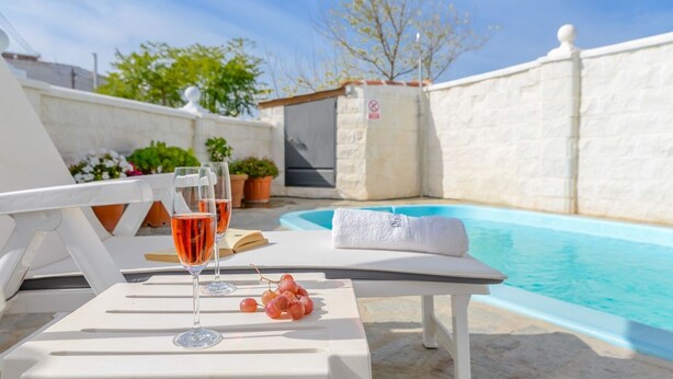 A poolside area with white lounge chairs, a table with a glass of rosé wine and grapes, and a towel. - Casa de la Abuela Gaucín by Ruralidays (Málaga)