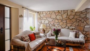 A living room with two sofas, a coffee table, and a stone wall. - Casa de la Abuela Gaucín by Ruralidays (Málaga)