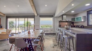 Eine moderne Küche mit einer großen Kochinsel, Barhocker und einem Essbereich mit einem langen Tisch und Stühlen.