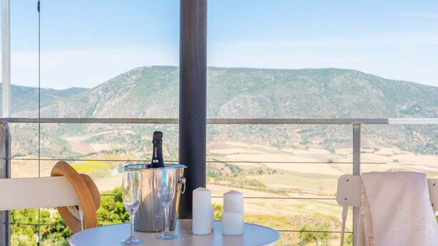 Un balcon avec une table dressée pour deux personnes, une bouteille de vin et des bougies.