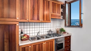 Une cuisine avec des meubles en bois, un pare-feu en carrelage, un évier, une cuisinière et une fenêtre donnant sur les bateaux.