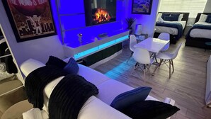 Moderni olohuone, jossa on litteänäyttöinen televisio, sohva, sohvapöytä ja takka.