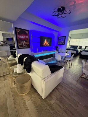 Ein modernes Wohnzimmer mit Flachbildfernseher, einer Couch, einem Couchtisch und einem Kamin.