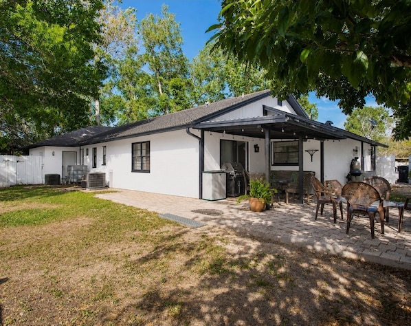 A single-story house with a covered patio, a grill, and outdoor seating.
