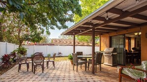 A patio area with a covered barbecue grill, outdoor furniture, and a brick floor. - House 3B2B (Tampa)