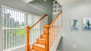Una escalera de madera con barandillas blancas y vistas al follaje exterior.