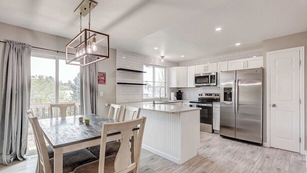 Una cocina moderna con armarios blancos, electrodomésticos de acero inoxidable y una mesa de comedor de madera.