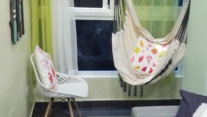 Ein Zimmer mit weißem Stuhl, einer Hängematte mit Fischmuster und einem Fenster mit Blick.