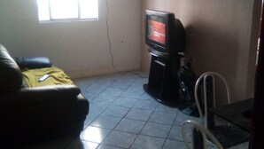 Un salon avec une télévision, un canapé et une fenêtre.