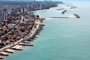 Un paisaje urbano costero con rascacielos, una playa y un litoral rocoso.