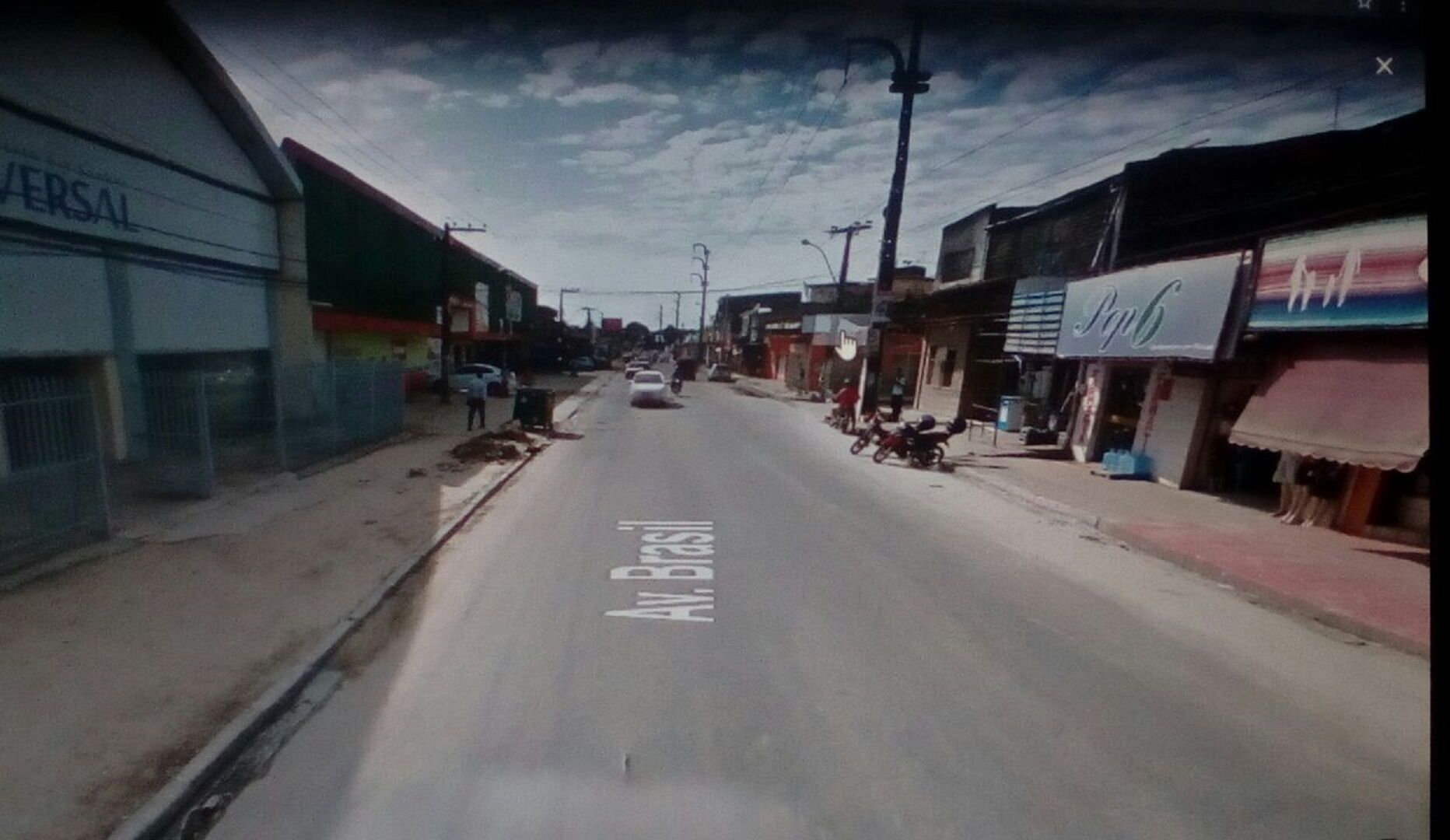 Una calle flanqueada por edificios, cielo despejado y una vía señalizada con "Av Brasil".