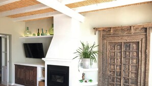 A living room with a fireplace, television, and decorative shelves. - 3-Bed Andalusian House with Private Pool & Garden! (Pizarra)